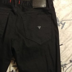 Black Guess skinny jeans with a hole.